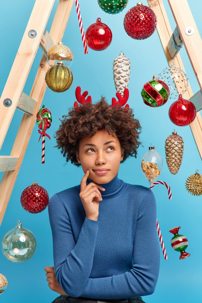 photo-serious-dark-skinned-woman-with-curly-hair-thinks-what-present-buy-husband-new-year-dressed-casual-turtleneck-reindeer-horns-surrounded-by-shiny-baubles-hanging-ladder-min.jpg